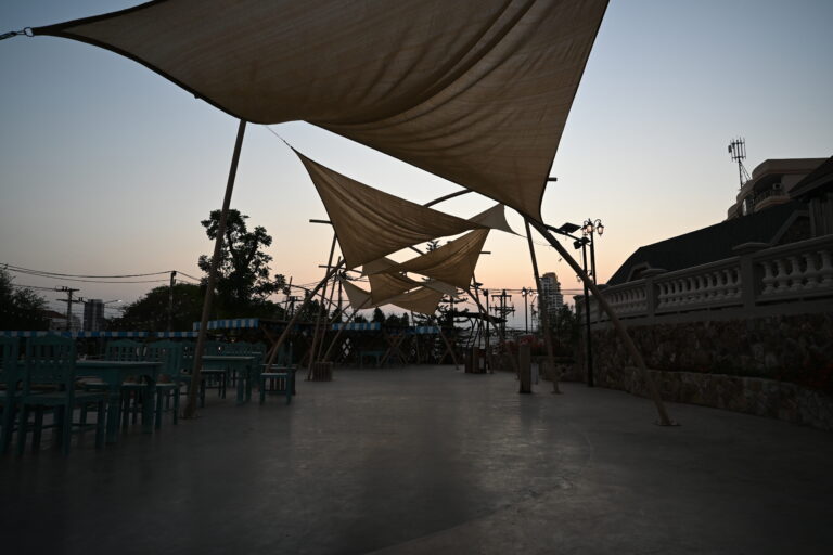 Seaside dining terrace at dusk with the sun setting over the water